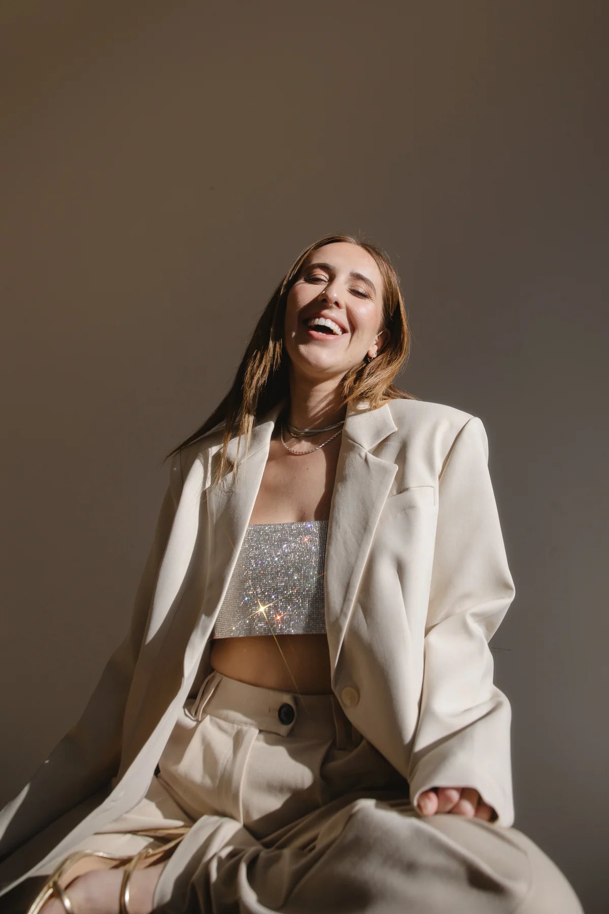 Elizabeth Faye laughing in a cream suit and a sparkling top