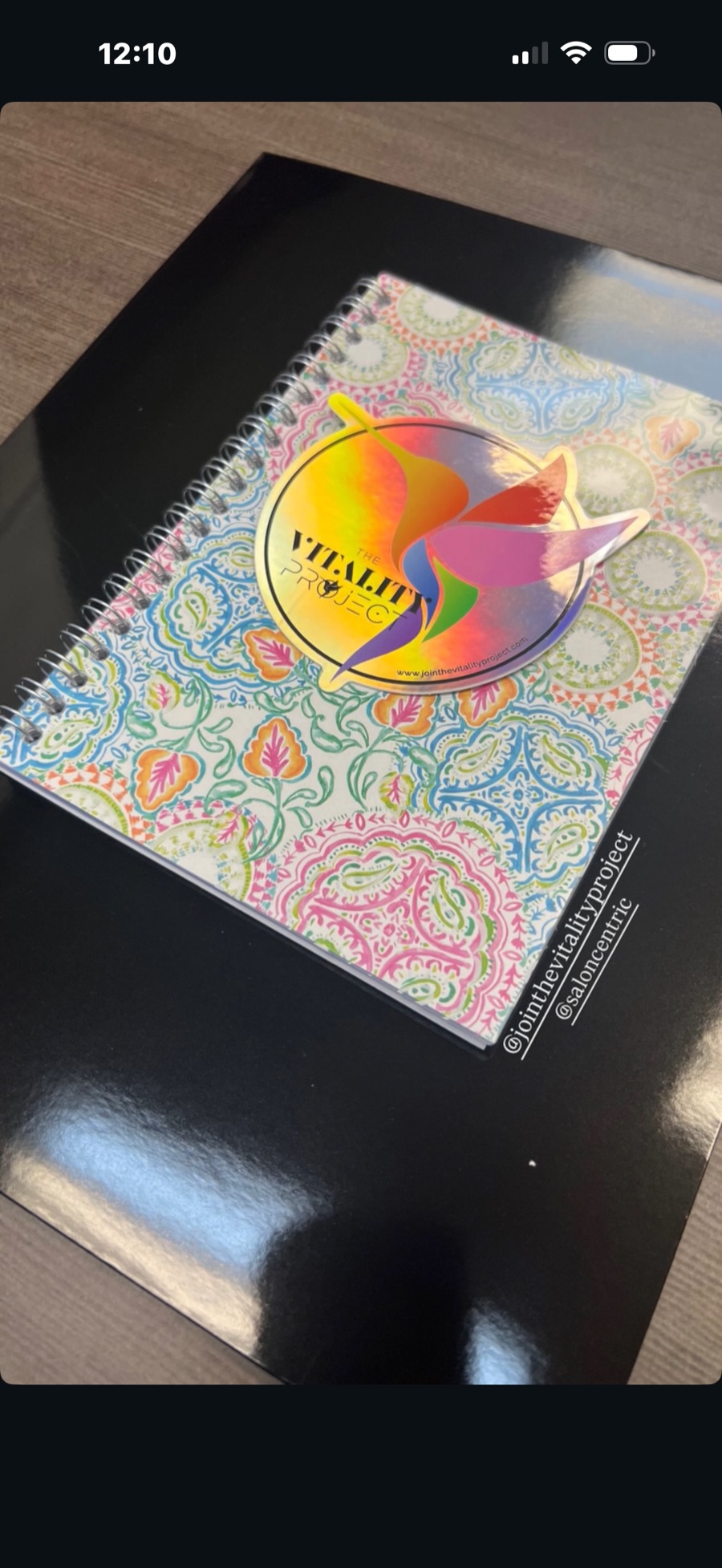 Flat lay of a patterned journal with The Vitality Project sticker
