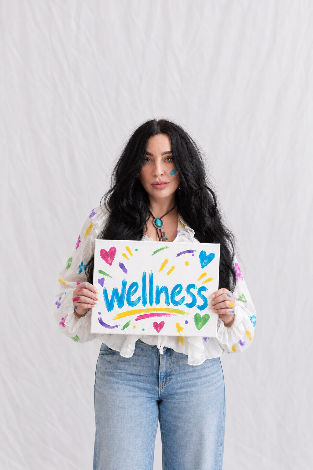 Tiffany holding a colorful hand-painted sign that reads Wellness