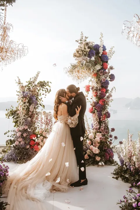 Elizabeth Faye and Derek kissing under a flower arch on their wedding day